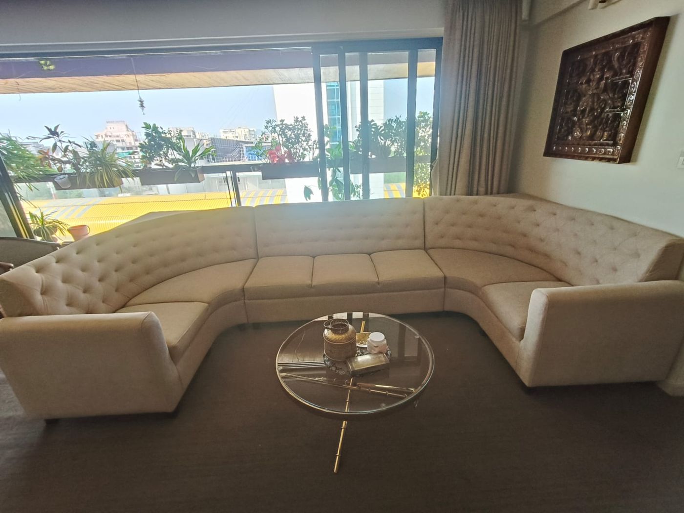 U-shaped button-tufted sofa around a glass table